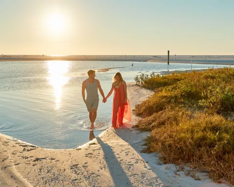 A couple holds hands at Tigertail Beach at sunset